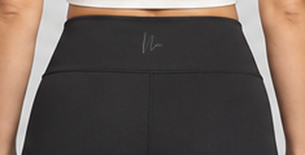 Close-up of the exact Double N monogram at the back waistband of the black Luxe Crossover Leggings.