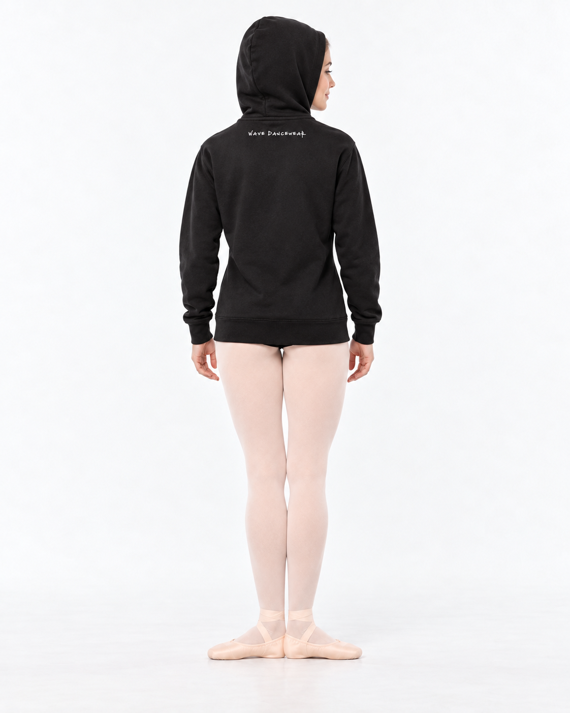 Back decoration mockup: ballet dancer in black fleece zip-up, hood up showing modest white Wave Dancewear back-neck wording, pink tights and slippers.